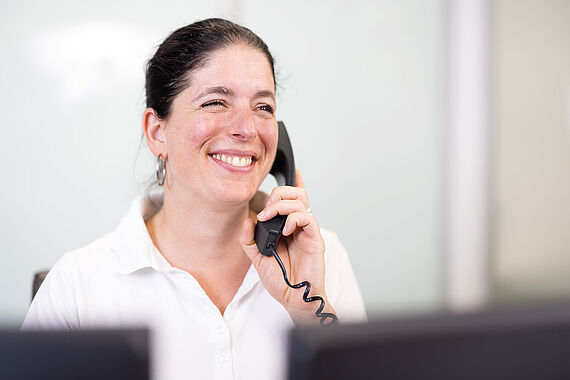 Mitarbeiterin telefoniert lächelnd an Rezeption
