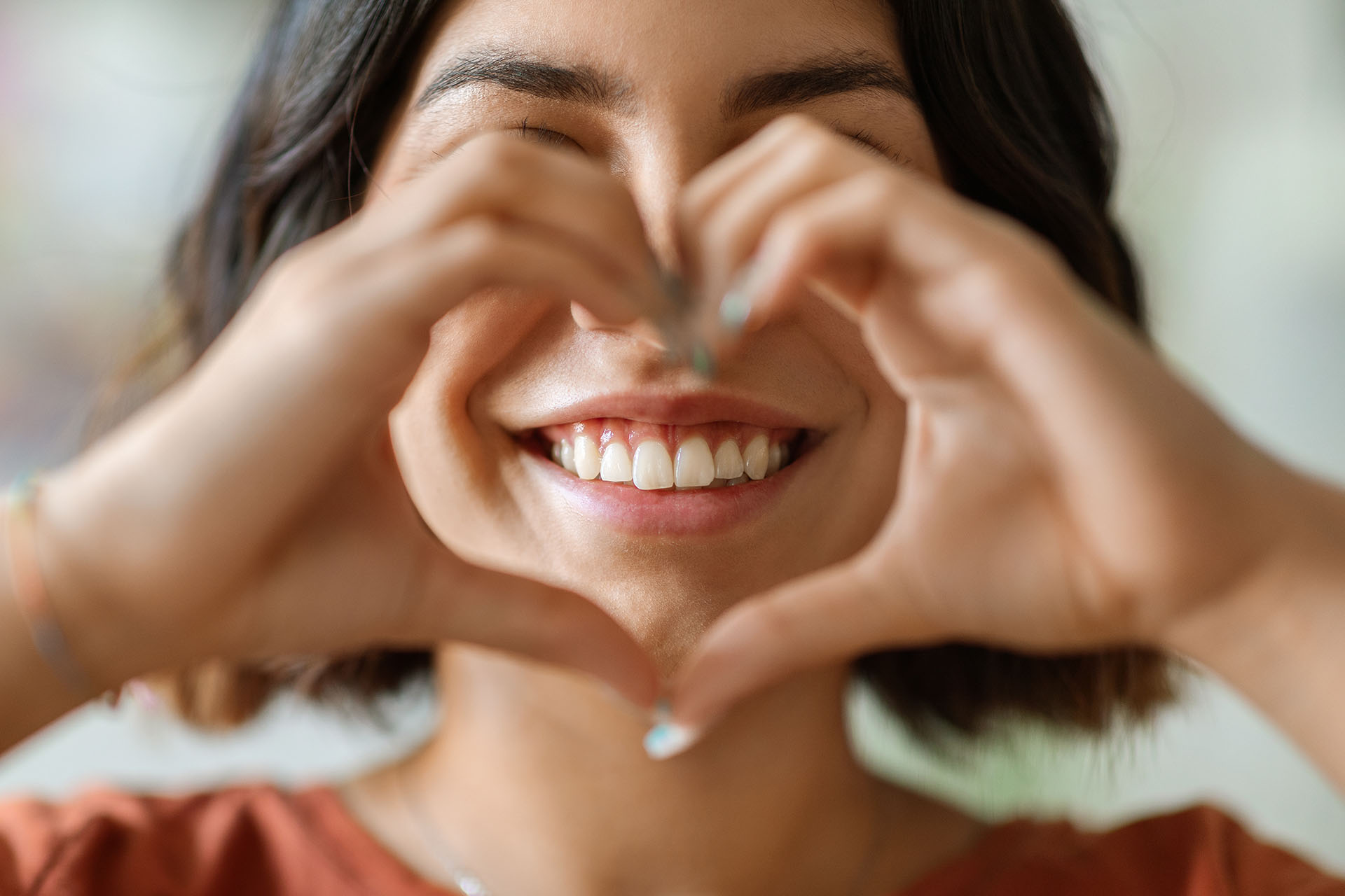 Frau lächelt und formt mit ihren Händen ein Herz